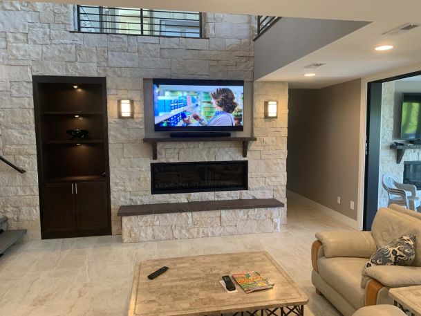 Living room area with dark wood shelves, tv, and shone walls