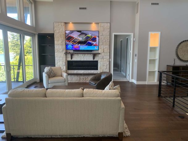 Living room, couch facing tv with wooden floors and stone backsplash