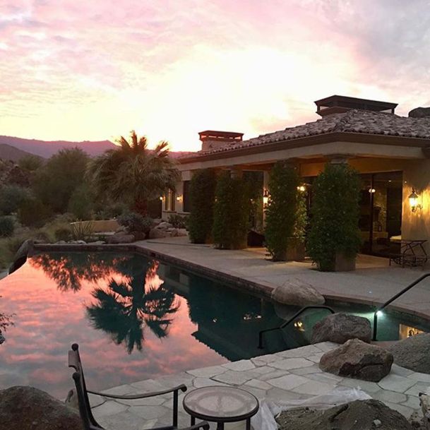 Sunset view of home with pool and palm trees
