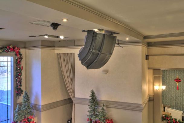 Up close view of ceiling speakers in front of tan walls