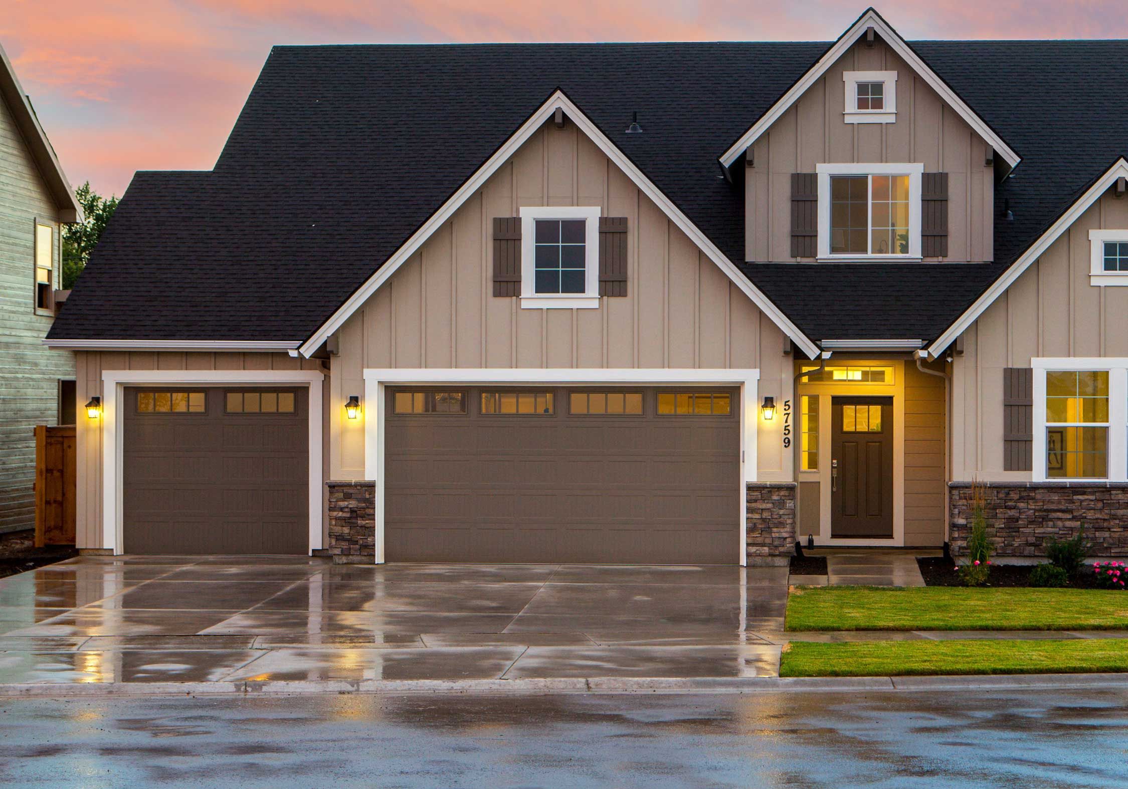 Brown home, brown garage doors, after rain storm, lights on